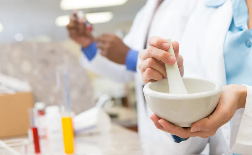 A pharmacist using a mortar and pestle to prepare medication